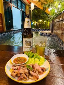 a bottle of beer and a plate of food and a drink at อีโฮสเทลบ้านช่น in Ban Chak Khamin