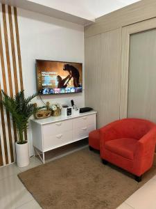 a living room with a red chair and a tv at Rich Staycation Makati in Manila