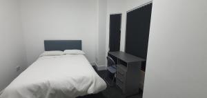 a bedroom with a white bed and a black cabinet at Coventry Rise Home in Coventry