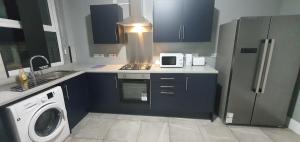 cocina con armarios azules, fogones y microondas en Coventry Rise Home en Coventry