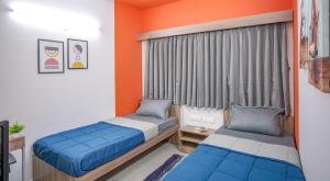 a bedroom with two beds and an orange wall at Yello! ITPL in Bangalore