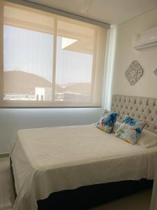Bett in einem Zimmer mit einem großen Fenster in der Unterkunft Samaria Club de playa Santa Marta , Colombia in Gaira