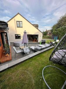 a backyard with a patio with chairs and an umbrella at Modern Harrogate house sleeps 10, cinema room & hot tub in Harrogate