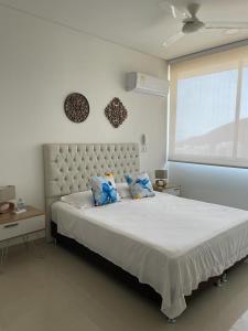 ein Schlafzimmer mit einem großen weißen Bett mit blauen Kissen in der Unterkunft Samaria Club de playa Santa Marta , Colombia in Gaira