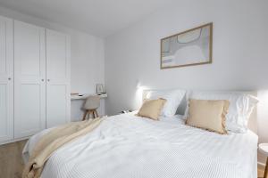 a white bedroom with a large white bed with two pillows at Fabryczna 19 by Farkas Apartments in Poznań