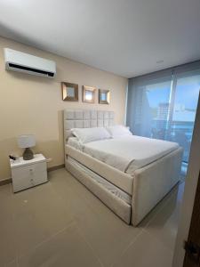 ein Schlafzimmer mit einem großen weißen Bett und einem Fenster in der Unterkunft Samaria Club de playa Santa Marta , Colombia in Gaira