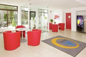 a lobby with red chairs and a table and a rug at Jugendgästehaus Mondsee in Mondsee