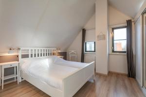 um quarto branco com uma cama branca e 2 janelas em Buitenplaats 27 Callantsoog em Callantsoog