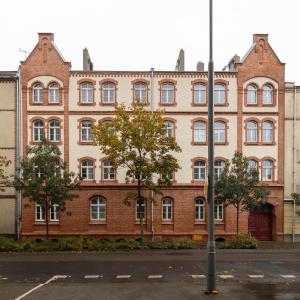 a large brick building with trees in front of it at Fabryczna 19 by Farkas Apartments in Poznań