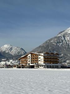 a large building in front of a snow covered mountain at Hotel Cafe-Zillertal in Strass im Zillertal