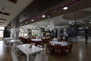 un restaurante con mesas y sillas blancas y lámparas de araña en Hotel 1 Maji en Pogradec