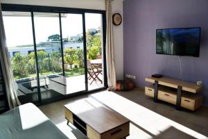 a living room with a tv and a large window at Charmant 2P de 45m2 au calme, Vue Mer Panoramique, Terrasse Privée 30m2, Piscine in Saint-Laurent-du-Var