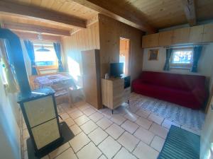 Habitación pequeña con sofá rojo y TV. en Appartamento al Tabià Pizal, en Santo Stefano di Cadore