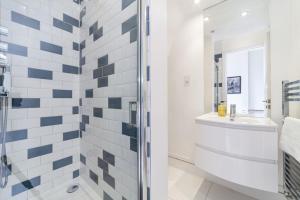 uma casa de banho branca com um chuveiro e um lavatório. em Charming 1 BR flat near Hyde Park em Londres