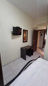Habitación con cama, escritorio y TV en la pared. en Obrava Guesthouse Kotroni Trikalon en Kotrónion