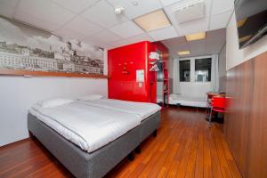 1 dormitorio con cama y pared roja en Omena Hotel Helsinki City Centre, en Helsinki