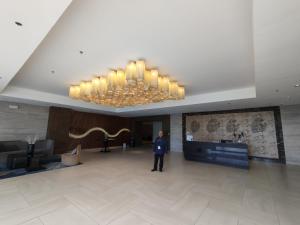 a man standing in a large lobby with a chandelier at Mactan Newtown Beach Condo by FJCIVO in Lapu Lapu City
