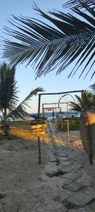 a volley ball goal on a beach with a palm tree at Bimba Chalés Pé na Areia - Guaibim-Ba in Guaibim