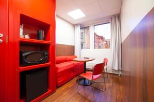 a red living room with a red couch and a table at Omena Hotel Helsinki City Centre in Helsinki