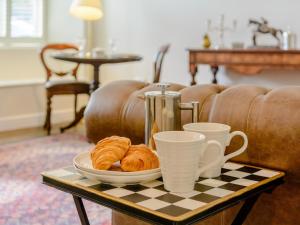 a table with a plate of croissants and two cups at 1 bed property in Tetbury 79151 in Tetbury