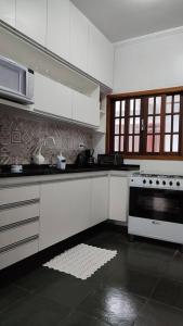 una cucina con armadi bianchi e piano cottura di excelente casa ótima localização a Ubatuba