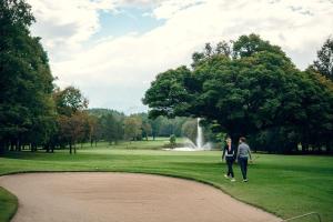 two people walking in a park with a fountain at Ilsenhof am Turnersee in Obersammelsdorf