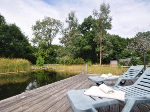 two lounge chairs on a wooden deck next to a pond at 2 Bed in Ledbury 77377 