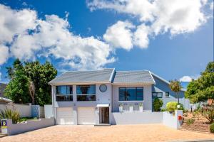 una casa blanca con un cielo azul y nubes en Suikerbos Guesthouse, en Ciudad del Cabo