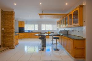 una cocina con armarios de madera y taburetes de bar en Suikerbos Guesthouse, en Ciudad del Cabo