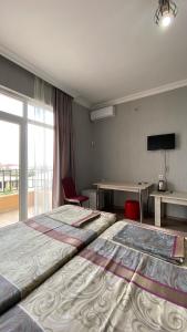 Cette chambre comprend deux lits, une table et une fenêtre. dans l'établissement ZUMA, à Batoumi