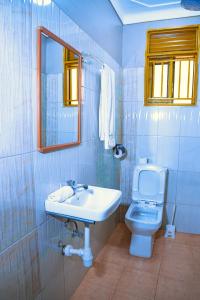 bagno con lavandino, servizi igienici e specchio di GOLDEN QUEST HOTEL a Entebbe