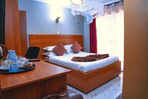 a bedroom with a bed and a desk with a desk at GOLDEN QUEST HOTEL in Entebbe