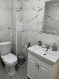 a white bathroom with a toilet and a mirror at Comfort plus in Almaty