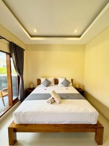 een slaapkamer met een bed met een teddybeer erop bij Dega Gardens in Canggu