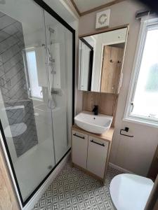 ein Badezimmer mit Waschbecken und Dusche in der Unterkunft The Retreat 16 - pet friendly, WiFi, and a bath - Golden Palm Resort - Meadow Lakes Caravan & Lodge Hire in Chapel Saint Leonards