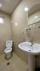 La salle de bains est pourvue d'un lavabo blanc et de toilettes. dans l'établissement ZUMA, à Batoumi