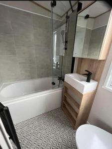 ein Badezimmer mit Waschbecken, Badewanne und Toilette in der Unterkunft The Retreat 16 - pet friendly, WiFi, and a bath - Golden Palm Resort - Meadow Lakes Caravan & Lodge Hire in Chapel Saint Leonards