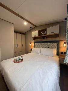 ein großes weißes Bett mit einem Blumentablett darauf in der Unterkunft The Retreat 16 - pet friendly, WiFi, and a bath - Golden Palm Resort - Meadow Lakes Caravan & Lodge Hire in Chapel Saint Leonards