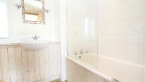 a white bathroom with a tub and a sink at Middleton Hall Cottage in Rhossili +18 photos