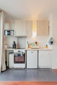 a kitchen with white cabinets and white appliances at Studio Doux et Cosy Paris in Gentilly