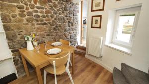 a dining room with a wooden table and a stone wall at Bwthyn Bach in The Mumbles