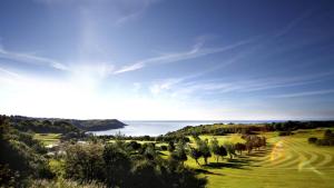 uma vista para um campo de golfe com o oceano ao fundo em Bwthyn Bach em The Mumbles