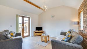 a living room with two couches and a tv at Daffodil Cottage in Penclawdd