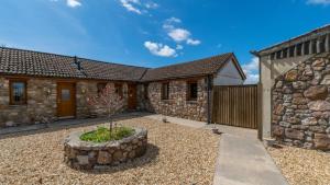 a stone house with a courtyard and a stone wall at Daffodil Cottage in Penclawdd