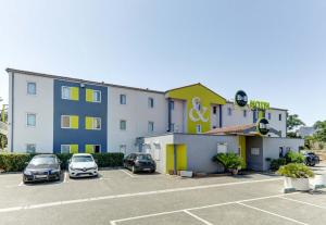 un hotel con coches estacionados en un estacionamiento en B&B HOTEL Fréjus Roquebrune-sur-Argens en Roquebrune-sur-Argens