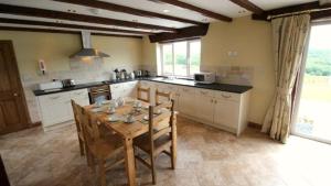 a large kitchen with a wooden table and chairs at Llanelen Farm Sleeps 2 in Llanrhidian