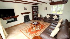 a living room with a leather couch and a fireplace at Llanelen Farm Sleeps 2 in Llanrhidian