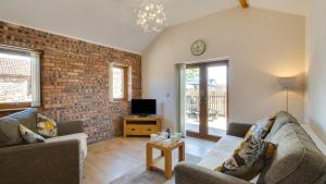 a living room with two couches and a brick wall at Bluebell Cottage in Penclawdd