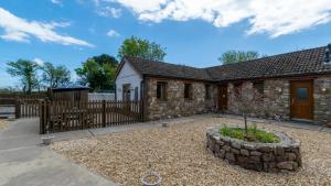 Bluebell Cottage في Penclawdd: بيت حجري مع بوابة خشبية وسياج