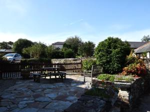 a patio with a table and benches in a garden at 3 bed in Bude TRVVV in Poughill